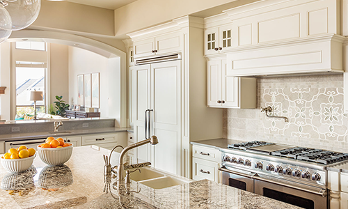 This image showcases a remodeled kitchen with a striking granite island, elegant custom cabinets, and beautiful wood floors. The design combines modern functionality with timeless elegance, creating a perfect space for cooking and entertaining.