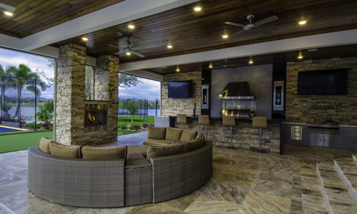 Beautiful roofed patio with marble floors, a bar, and a built-in fireplace